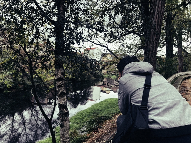 A picture of myself from the back while I try to take a picture of a nice river reflection from a building