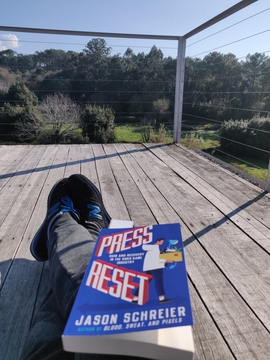 A picture of me resting a book called Press Reset on my legs while looking at the horizon.